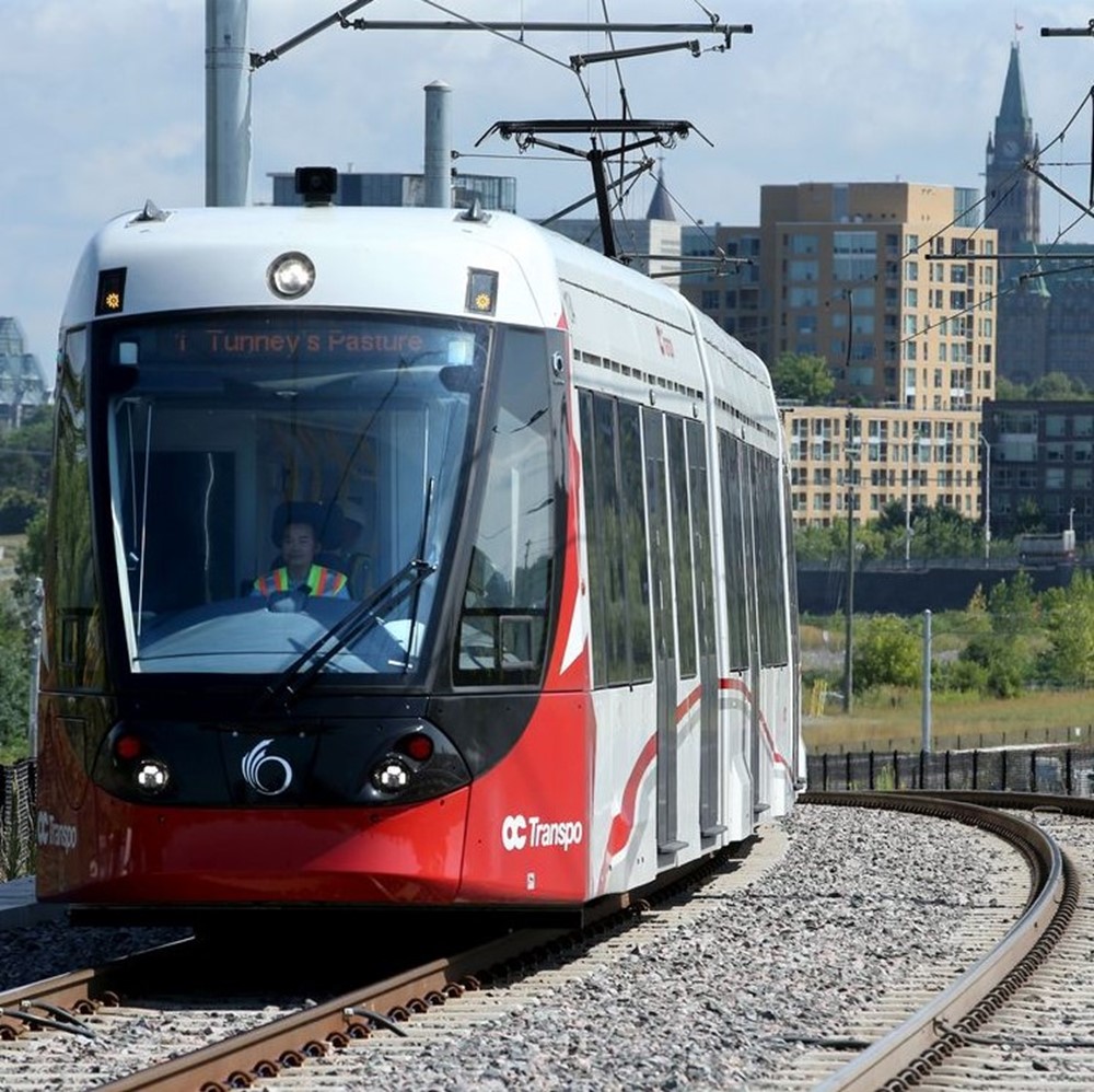 Ottawa light-rail train with a city skyline in the background.